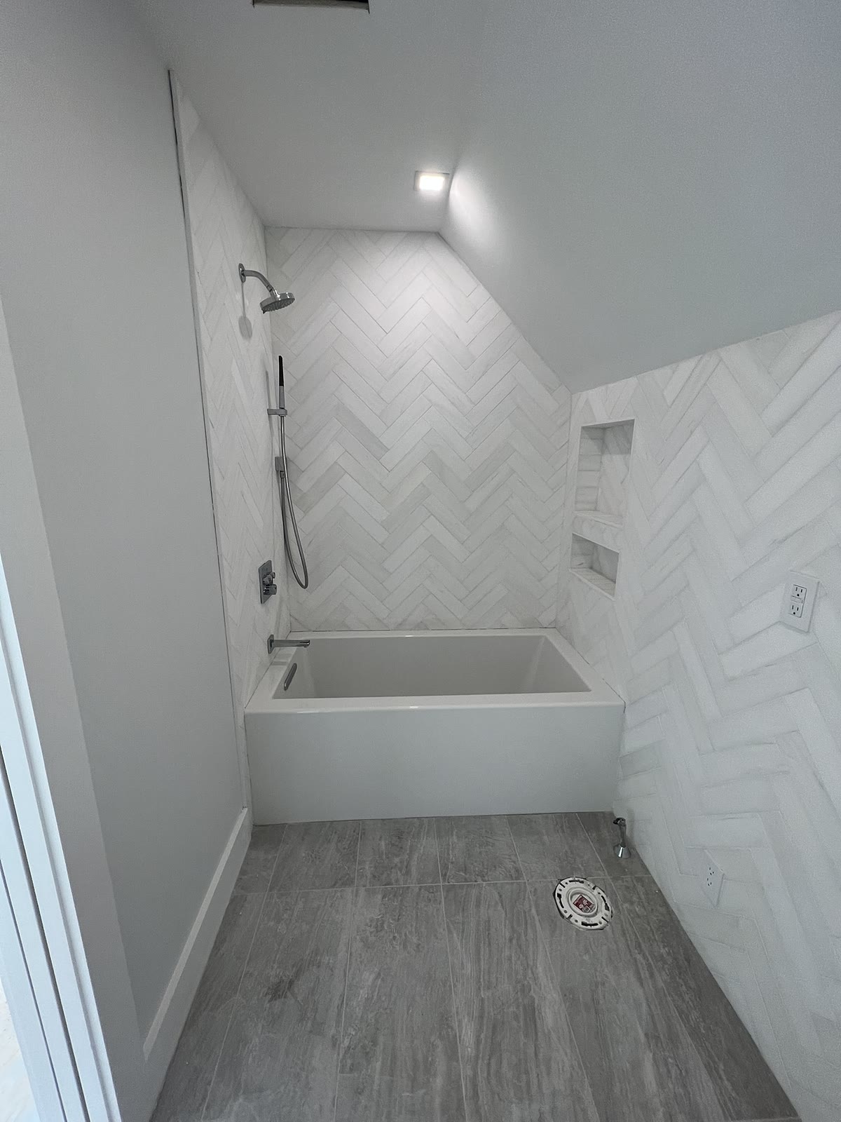 White herringbone tile tub and shower with custom niche