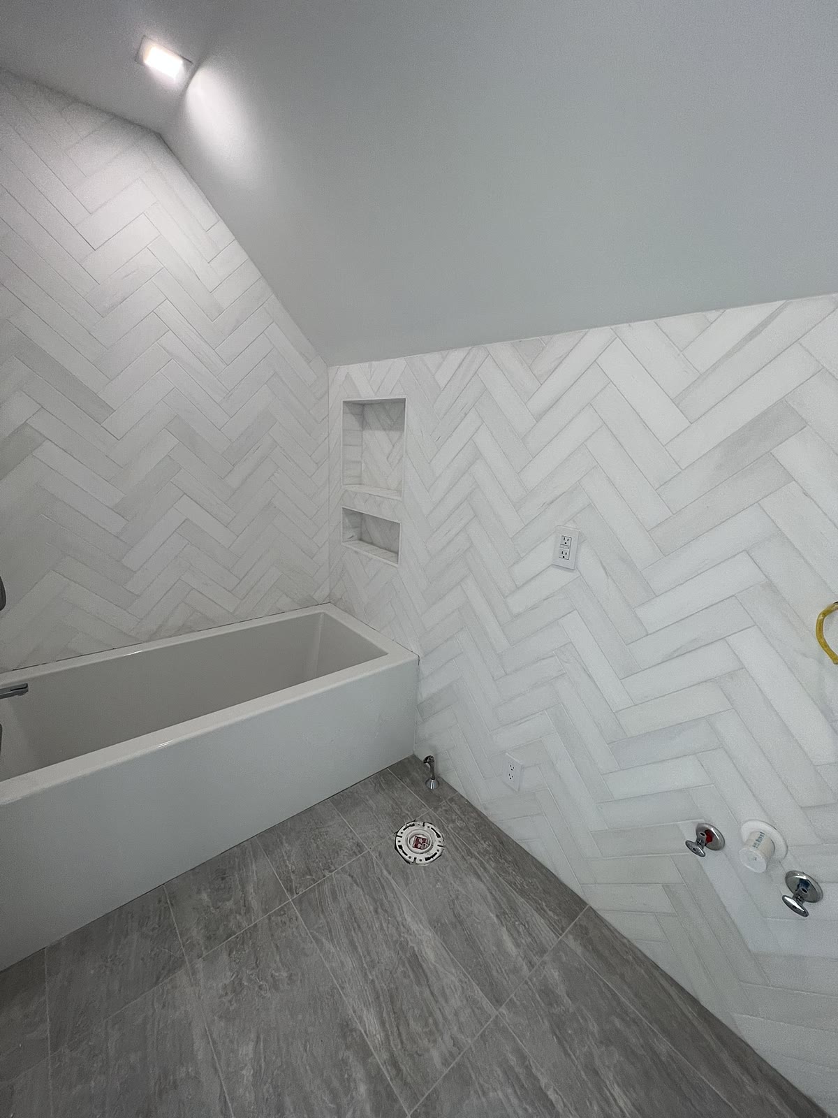 White herringbone tile bathroom with built-in niche shelving